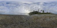 a view of the beach at low tide with rocks, trees and a sky background