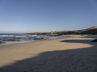 a view of a beach that has footprints in the sand and waves coming to shore