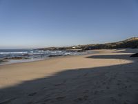 a view of a beach that has footprints in the sand and waves coming to shore