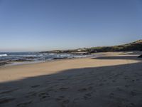 a view of a beach that has footprints in the sand and waves coming to shore