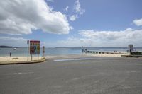 a beach road that has a sign with a picture on it and a boat at the water's edge