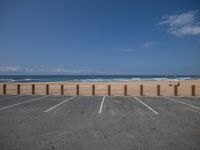 a person walking along the beach next to a fence, with ocean in background and people on the beach