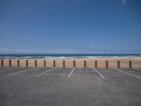 a person walking along the beach next to a fence, with ocean in background and people on the beach