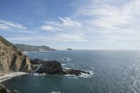 an ocean is seen with rocky shoreline and the water below it, with waves coming in from the ocean and rocks on either side