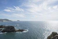 an ocean is seen with rocky shoreline and the water below it, with waves coming in from the ocean and rocks on either side