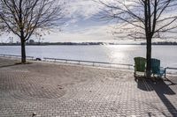 a bench and chair sitting on the curb by the water with benches to sit and watch