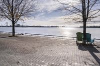 a bench and chair sitting on the curb by the water with benches to sit and watch