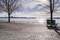 a bench and chair sitting on the curb by the water with benches to sit and watch