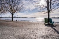 a bench and chair sitting on the curb by the water with benches to sit and watch