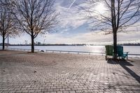 a bench and chair sitting on the curb by the water with benches to sit and watch