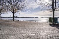 a bench and chair sitting on the curb by the water with benches to sit and watch