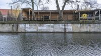 the boat is sitting on the water near the building under construction in front of the bridge