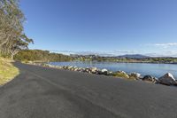 a bike path with a view of a waterway and mountains in the background with trees