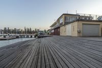 a boat dock with a wooden floor and fenced in area next to water and buildings