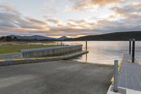 there is a boat dock next to the water and mountains at sunset over the water