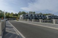 an empty road with a fenced in building behind it and a white van parked at the side