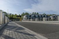 an empty road with a fenced in building behind it and a white van parked at the side