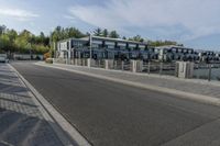 an empty road with a fenced in building behind it and a white van parked at the side