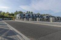 an empty road with a fenced in building behind it and a white van parked at the side