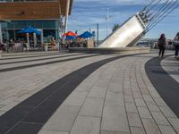 a long walkway with multiple lines on it along the side of a building that has people walking