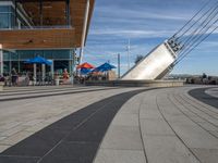 a long walkway with multiple lines on it along the side of a building that has people walking