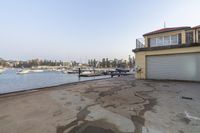 a view of a building near the water and boats in the bay with a house that has a deck and balcony