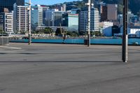 a bus is driving by an empty road near a river and city skyline in the background