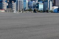 a bus is driving by an empty road near a river and city skyline in the background