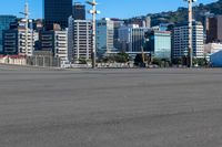 a bus is driving by an empty road near a river and city skyline in the background