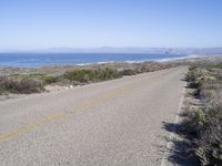 a bicycle lies in the middle of a road near the ocean and desert in california