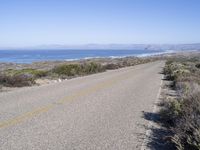 a bicycle lies in the middle of a road near the ocean and desert in california