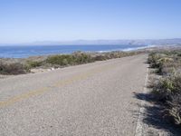 a bicycle lies in the middle of a road near the ocean and desert in california