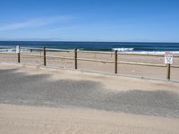 a paved beach with a fence in front of it and the ocean in the distance