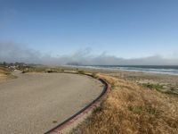 a fire hydrant near a paved beach with a long winding road in the foreground