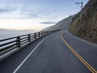 the two lane winding road is made of metal bars and posts with railings, and has mountains on both sides of it