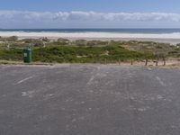 a car park with the ocean and beach in the background near the sandy shore line