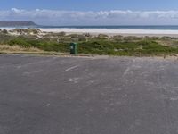 a car park with the ocean and beach in the background near the sandy shore line