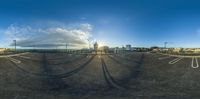 a large parking lot with parking lights near some docks and clouds in the background and the sun rising