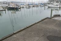 a man in an orange jacket standing at a dock next to a marina filled with boats