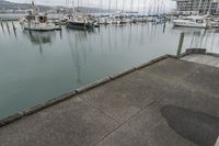 a man in an orange jacket standing at a dock next to a marina filled with boats