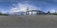 the view of a large bridge from below with a blue sky background and clouds over it