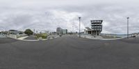 a view of the street with buildings on the side and boats in the distance, taken in a fisheye lens