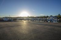 a parking lot with some boats parked on the side of it and the sun setting