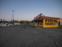 an empty store front that is full of fish and a market sign on it at dusk