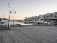 a pier with boats and buildings at sunset in the background, at a pier, there is an older looking building and several other apartments