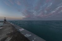 a view of the sea next to a concrete pier that is almost on its clifftop