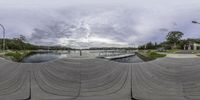 fisheye view of a river and boat dock and some buildings with a bridge in the distance