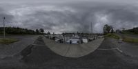 a picture of an empty street with boats parked by a fenced in area on a cloudy day