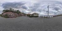 a 360 - spherical lens with buildings in the background and clouds overhead, and people outside