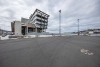 a parking lot and a building on the waterfront near water and buildings under a cloudy sky